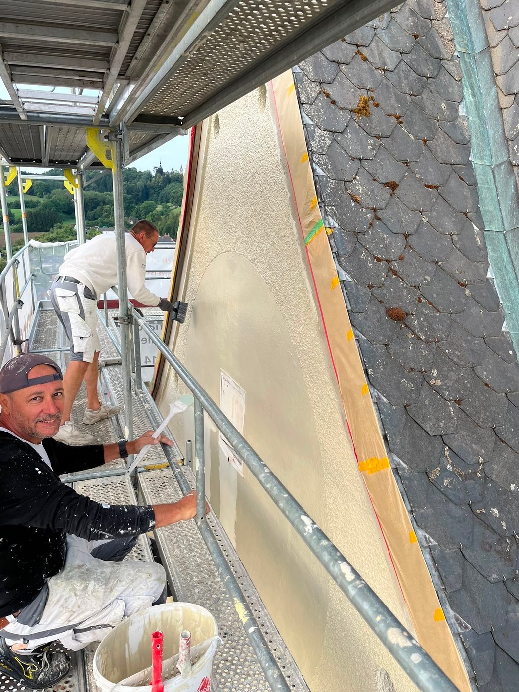 Facharbeiter auf dem Gerüst bei den Malerarbeiten an der Turmfassade