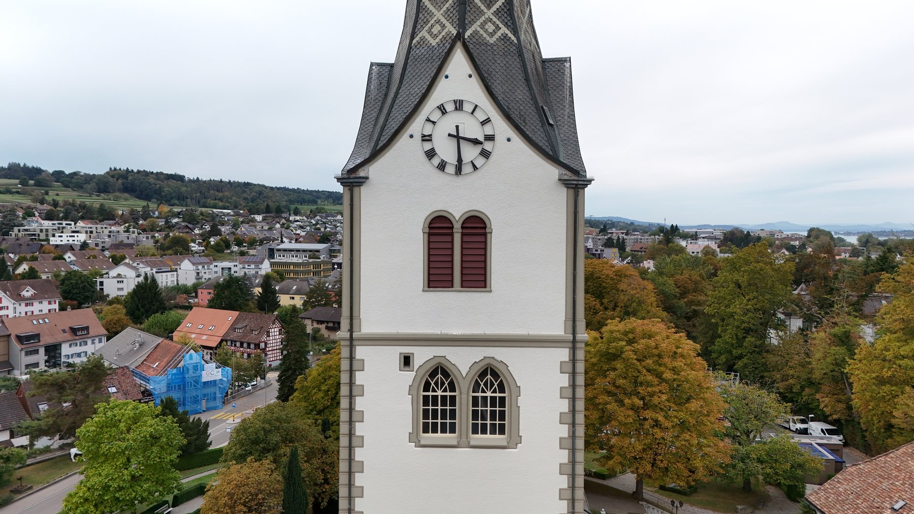 Turmfassade mit hellbeigen Flächen, grüngrauen Gliederungen und rotbraunen Fensterläden